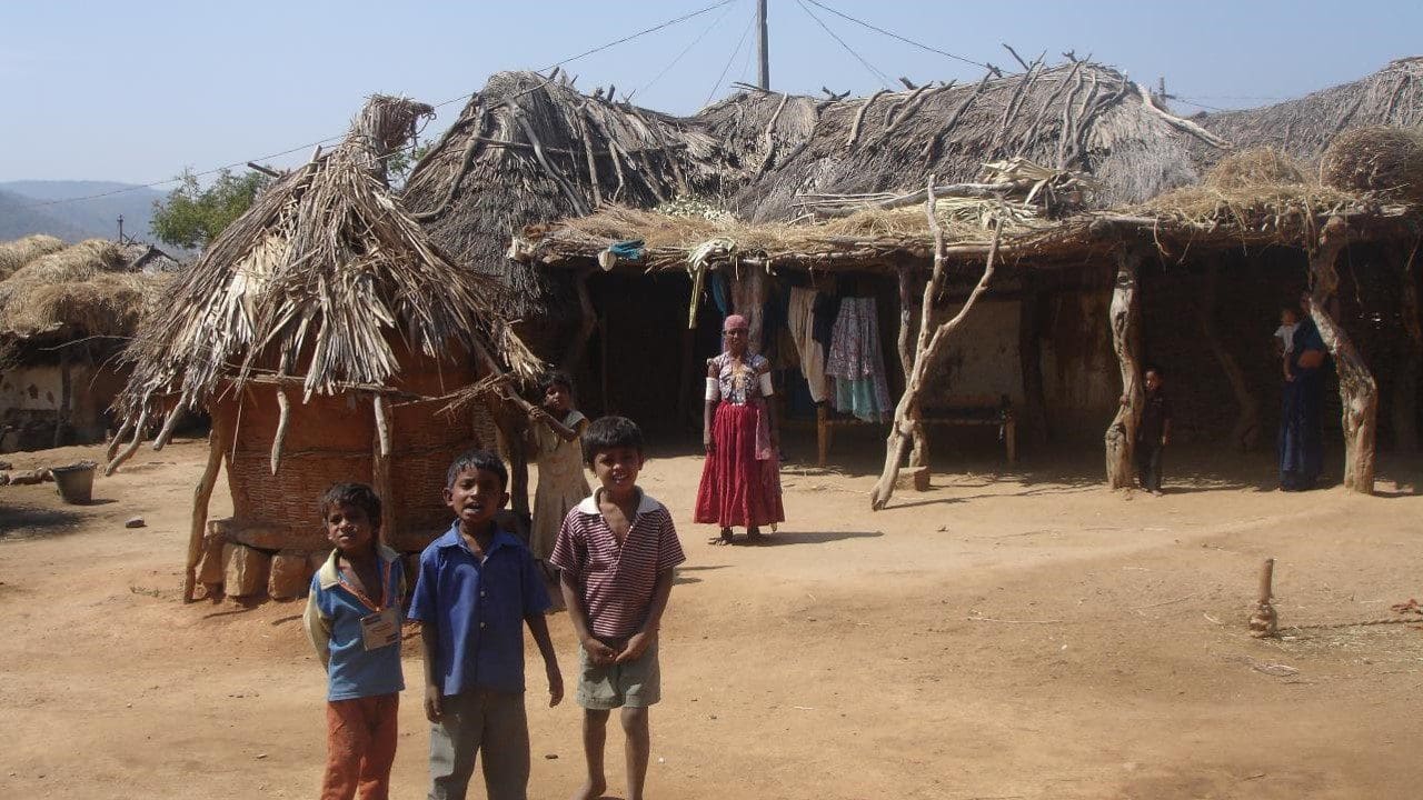 A group of people standing in front of a hut.