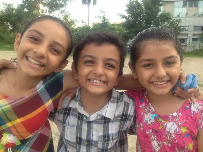 Three children smiling for a picture together.