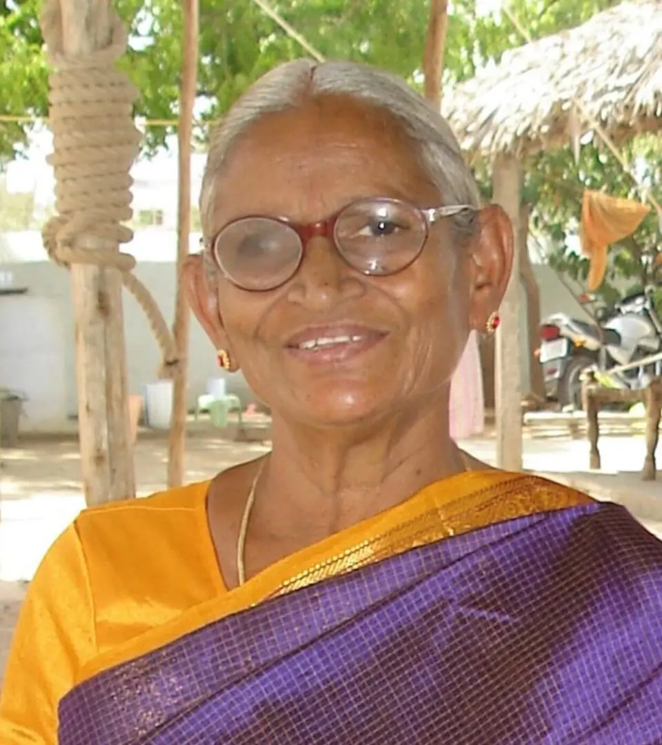 A woman in yellow and purple is smiling.