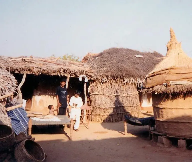 A group of people standing in front of some huts.