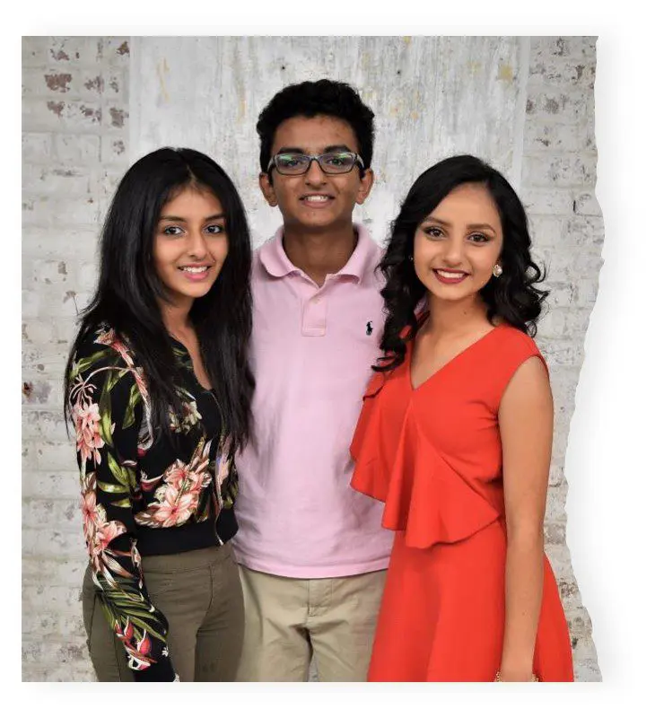 Three people posing for a picture in front of a brick wall.