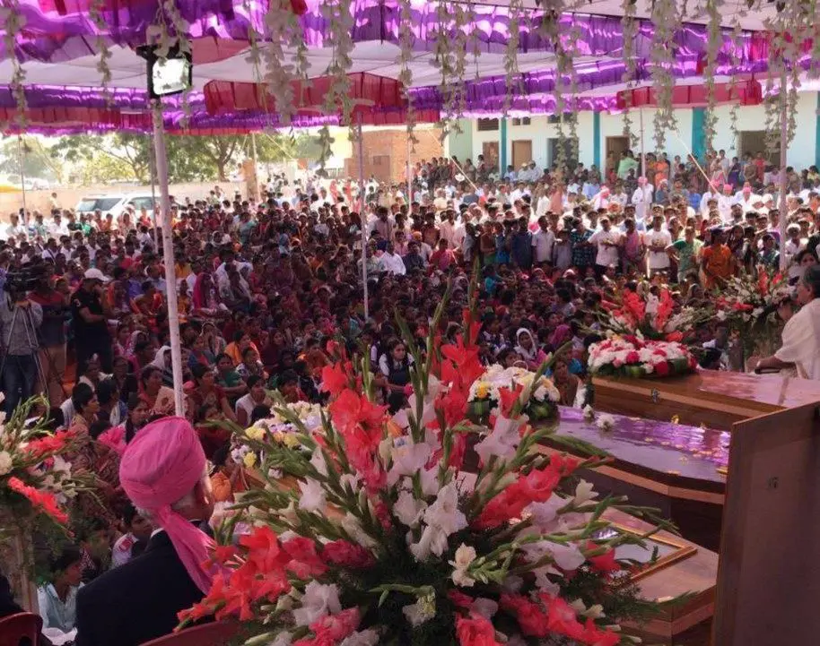 A crowd of people gathered around a bunch of flowers.