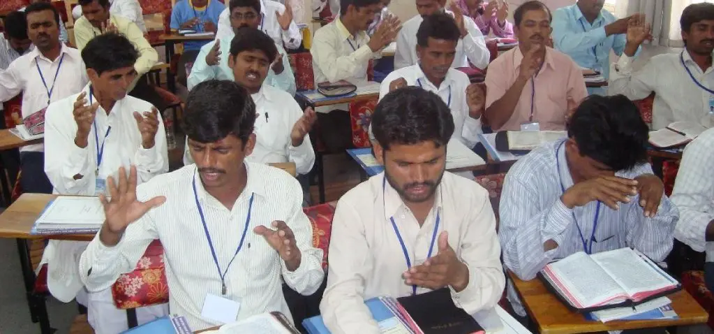 A group of people sitting in rows at tables.