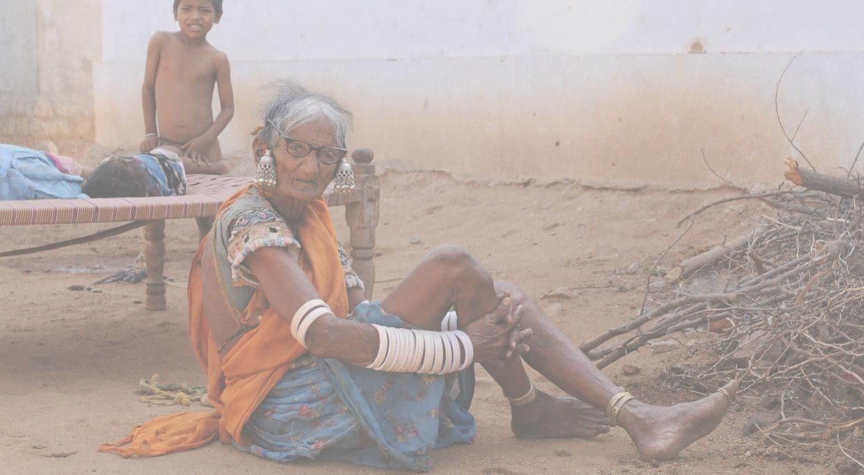 A woman sitting on the ground with her arm around another person.