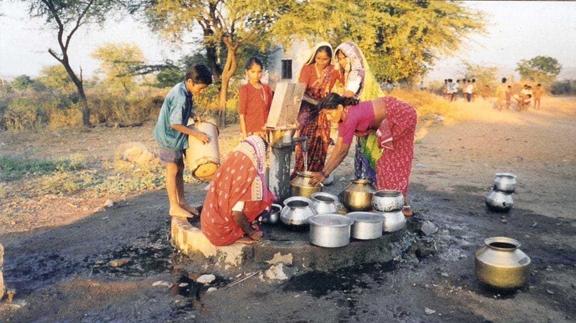 A group of people standing around cooking food.