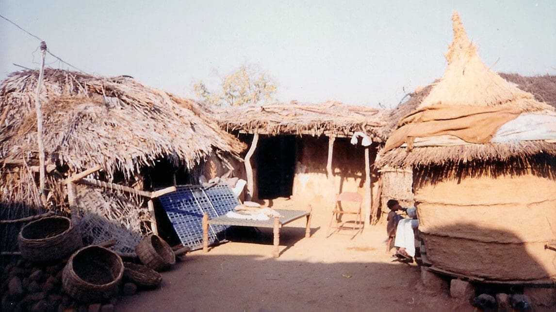 A hut with two thatched roofs and a hammock.