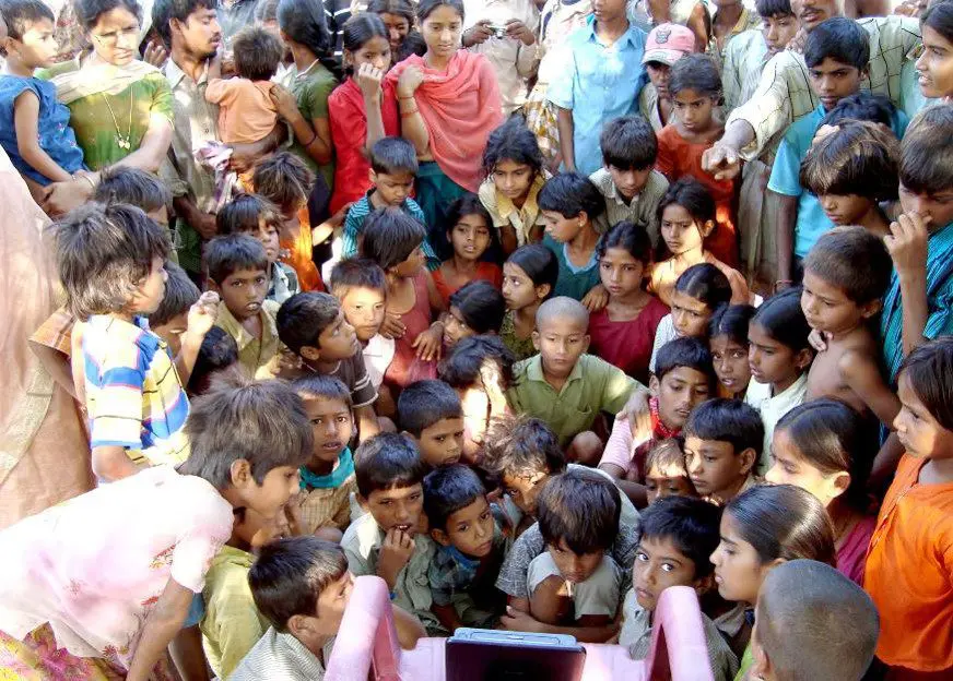 A group of children gathered around a laptop.