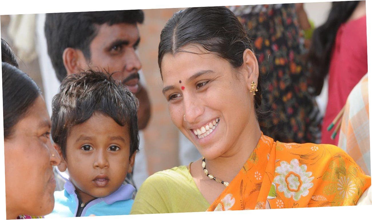 A woman smiles while holding her child.