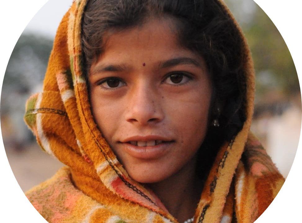 A young girl wearing a yellow and orange blanket.