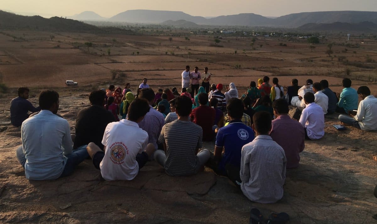 A group of people sitting on top of a hill.