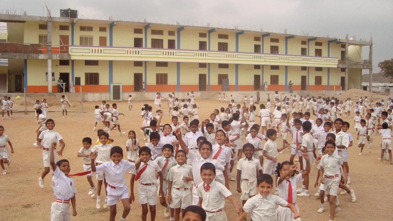 A group of children in white uniforms are standing outside.