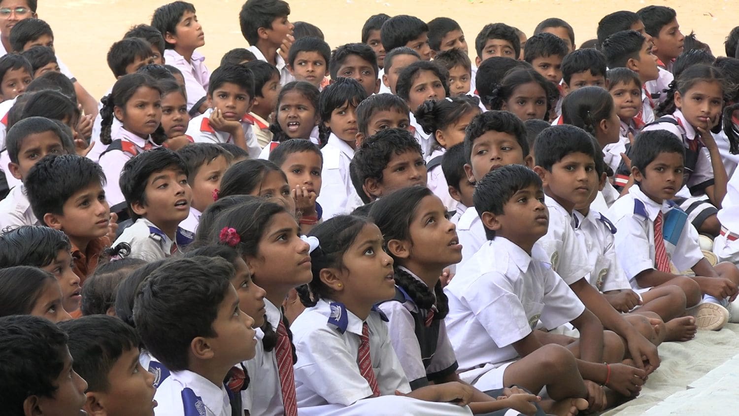 A group of children sitting in front of each other.