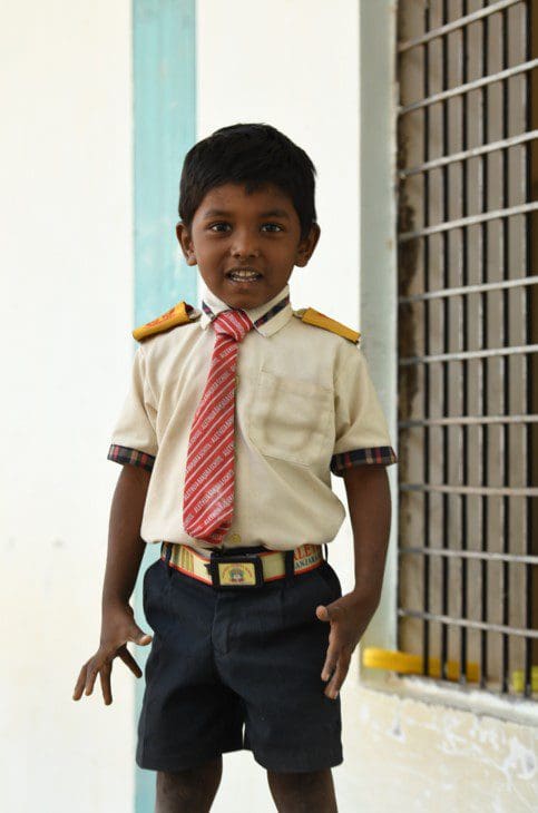 A young boy in uniform standing next to a wall.