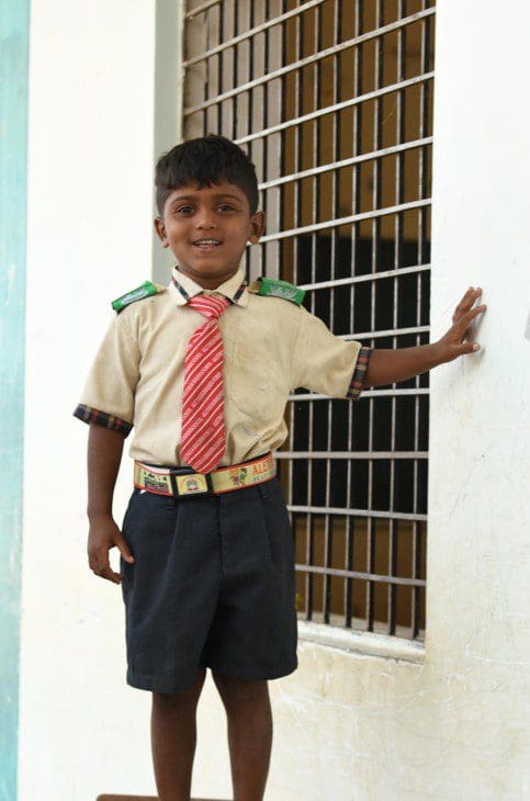 A young boy in uniform standing next to a window.