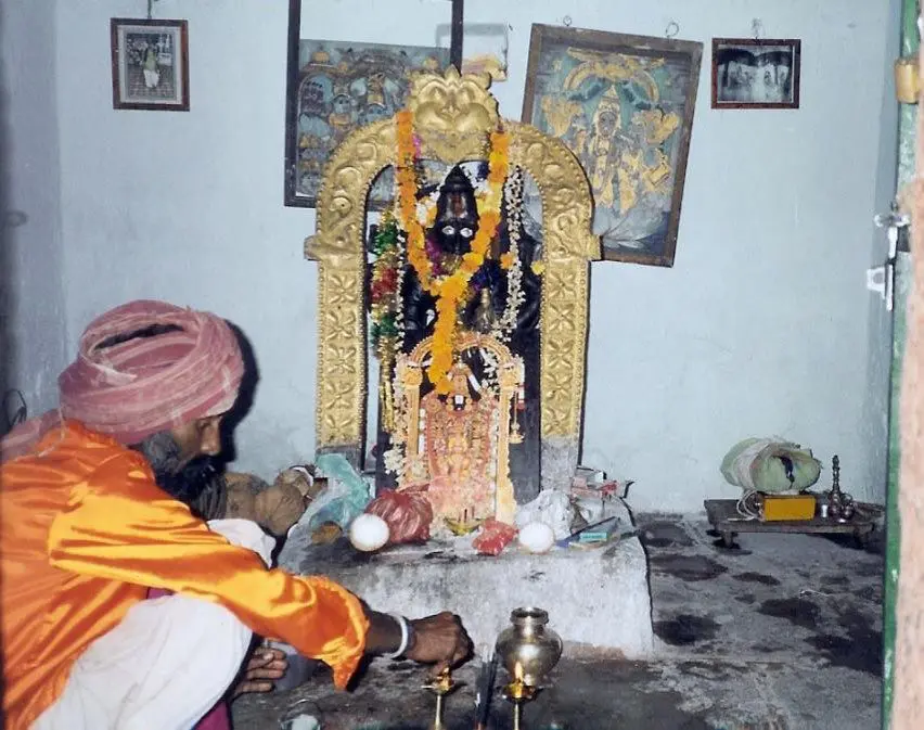 A man in orange and yellow robes standing next to an altar.