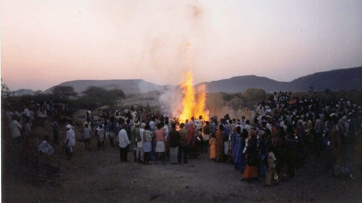 A crowd of people standing around a fire.