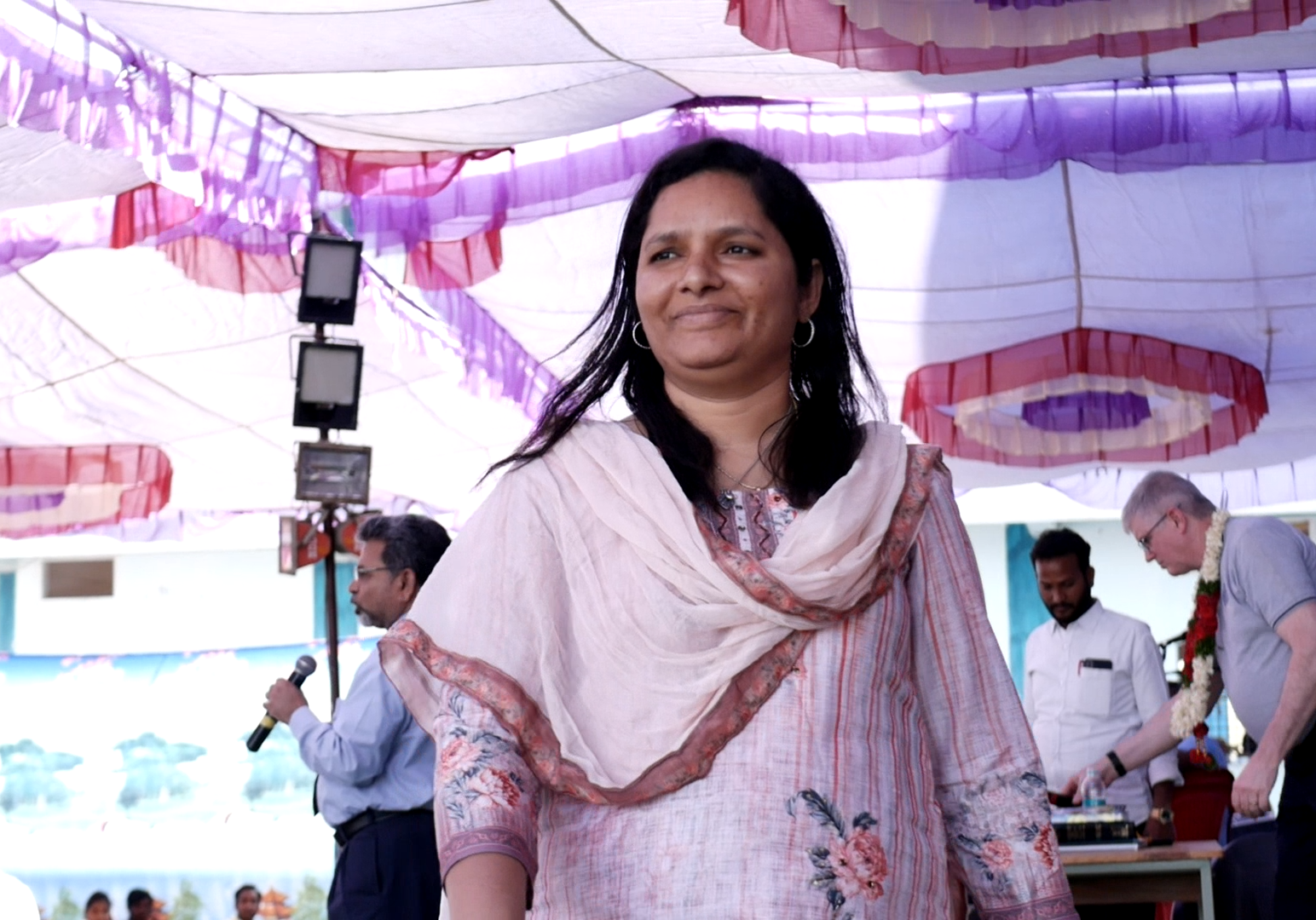 A woman in white dress standing under an umbrella.