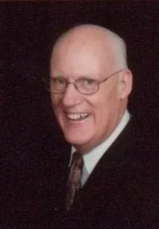 A man in a suit and tie smiling for the camera.