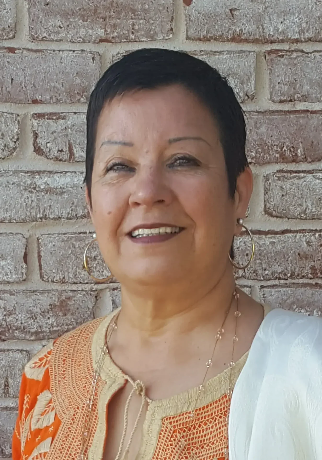 A woman with short hair wearing an orange and white outfit.