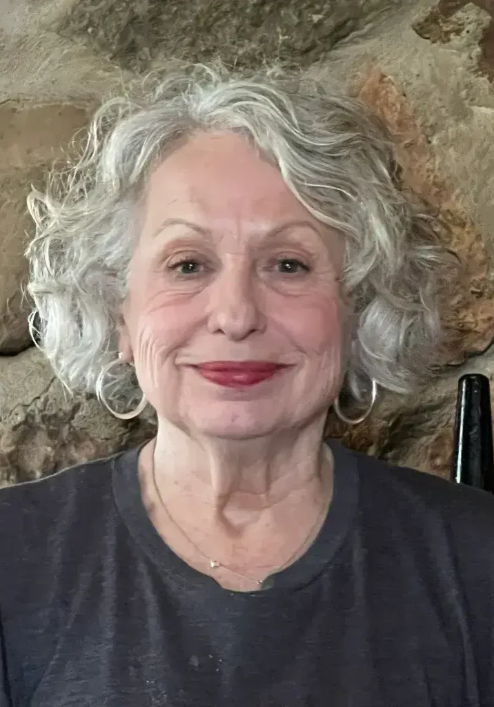 A woman with gray hair is smiling for the camera.