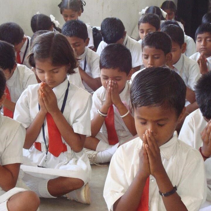 A group of children sitting in the floor praying.